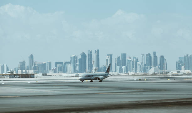 Qatar Airways aircraft with downtown skyscrapers on the background arriving in Doha capital city in Hamad International Airport, Doha, Qatar. stock photo