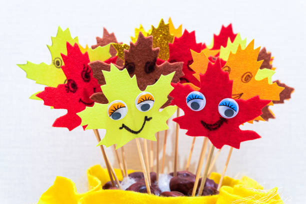 istock Red and yellow autumn soft cloth leaves stand on sticks. Leaf with face. 1278143329