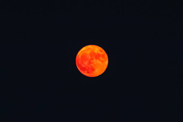 Thick orange haze over blurry orange full moon, reduced visibility from smoke and blazing record wildfires, San Francisco, California, United States