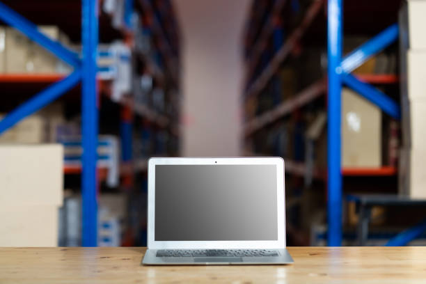 istock Personal laptop computer in warehouse store. Warehouse with Rows of Shelves and Cardboard Boxes 1278175764