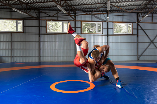 The concept of fair wrestling. Two greco-roman  wrestlers in red and blue uniform wrestling   on a wrestling carpet in the gym.
