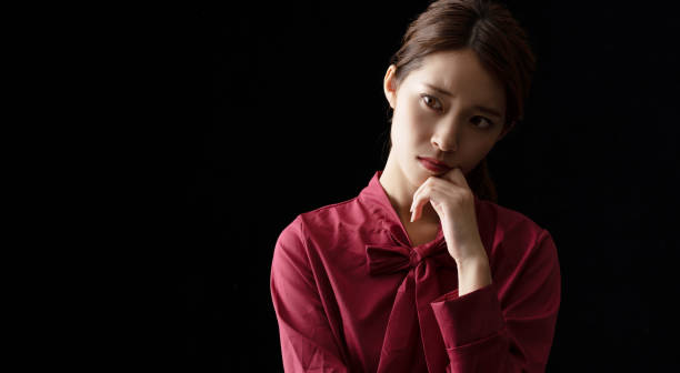 Troubled asian girl on black background.