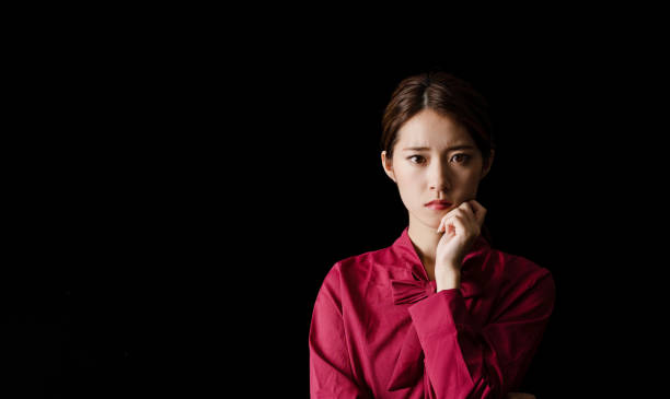 istock Troubled asian girl on black background. 1278200149