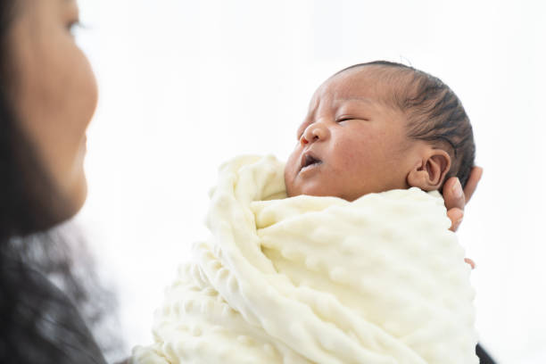 mother holding and looking to her cute african american newborn baby while her baby is covering a blanket - family american culture african culture black imagens e fotografias de stock