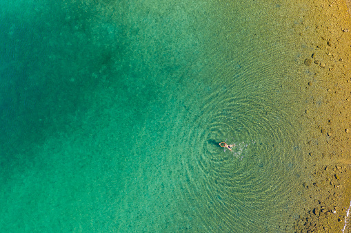 Aerial view of a girl is swimming in the clear sea of Brijuni National Park in Croatian Adriatic