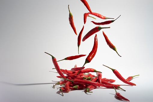 Set with fresh red chili peppers falling against white background