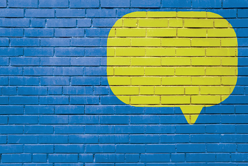 Brick Wall Speech Bubble Mural Text Message Copy Space Textured Background. Blue and Yellow Background.