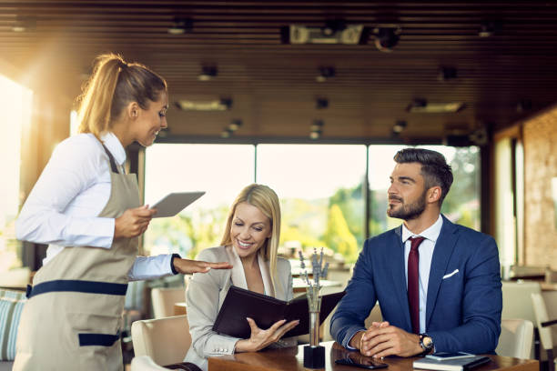 istock Business couple talking to waitress while choosing order from a menu in a restaurant. 1278210933