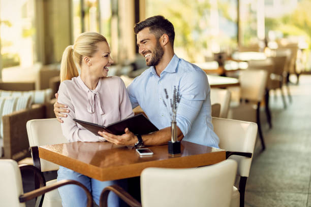 istock Happy couple talking while choosing order form a menu in a cafe. 1278211102