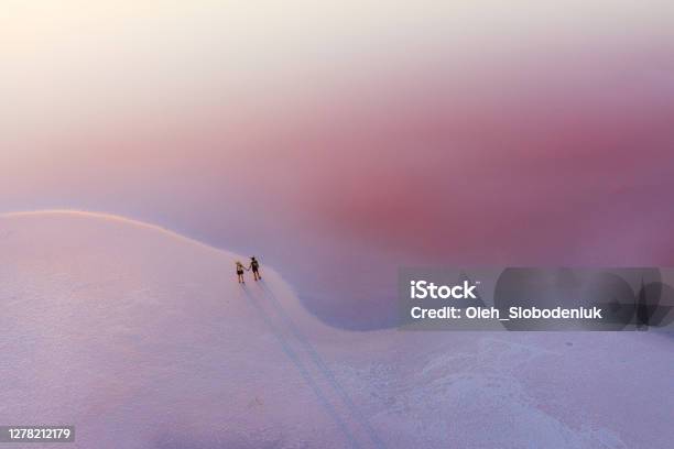 Scenic Aerial View Of Couple Walking On Pink Salt Lake Stock Photo - Download Image Now