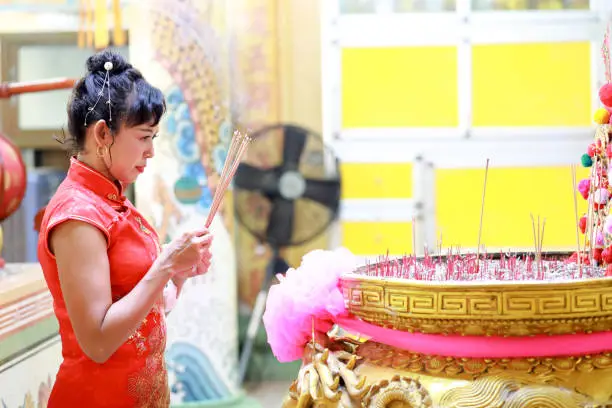 Photo of Portrait woman with incense in hand at the Chinese shrine background. Chinese new year festival concept.