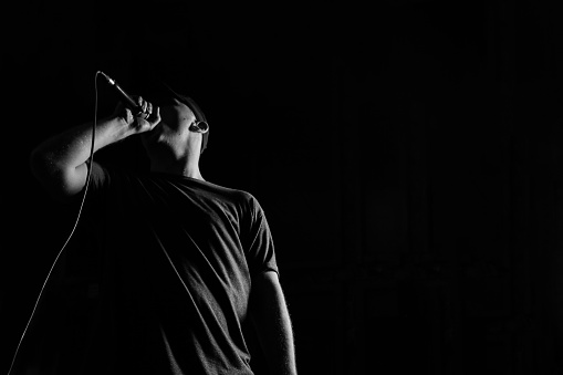 Male singing isolated on black background, studio shoot, black and white image.