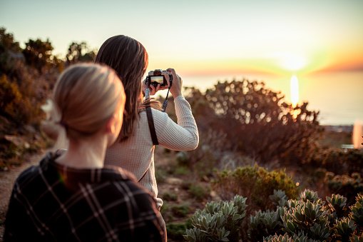 Young women enjoying and photographing the sunset