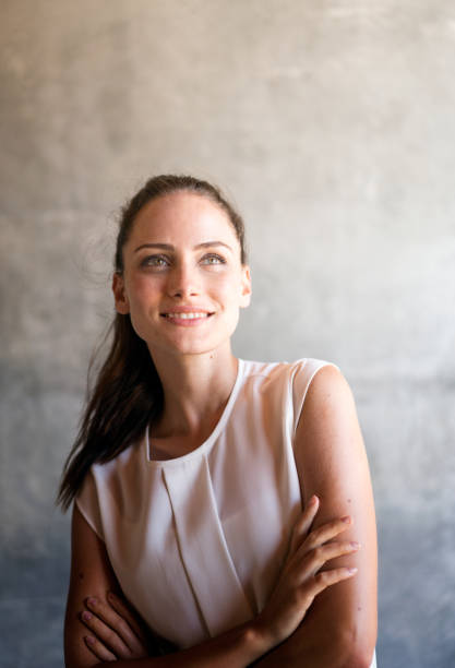 Smiling woman with arms crossed while day dreaming