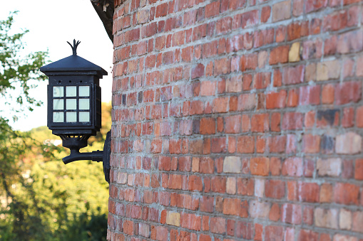 Old steel electric lantern attached to red brick wall