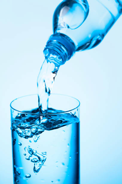 istock Pouring water from a bottle into glass on a blue background. 1278232679