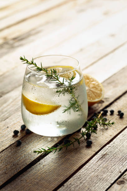 istock Alcohol drink (gin tonic cocktail) with lemon, juniper branch, and ice on rustic wooden table. 1278232696
