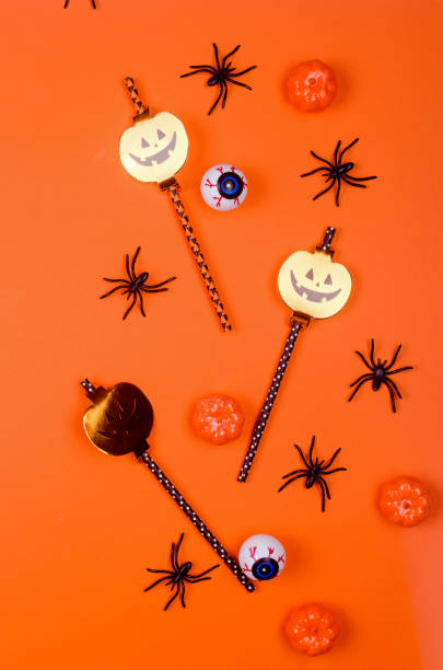 istock Halloween flat lay composition with pumpkins, drink straws, spiders, confetti, treat. 1278233011