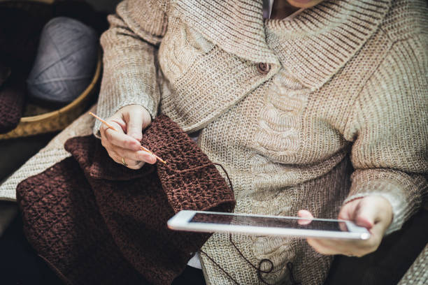 азиатская старуха вязание крючком с таплетом дома - grandmother knitting senior women senior adult стоковые фото и изображения