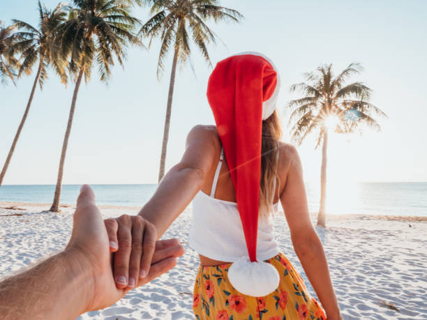 Couple holding hands on beach at Christmas stock photo