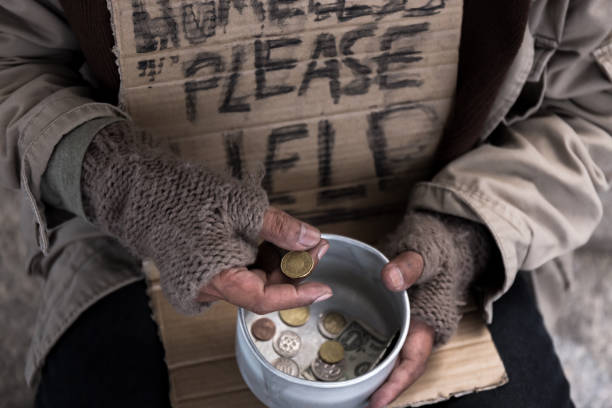 beggar homeless hold dollar money coin from his box sign of sadness unhappy from abandon and alone old man in dirty environment in business city concept stock photo