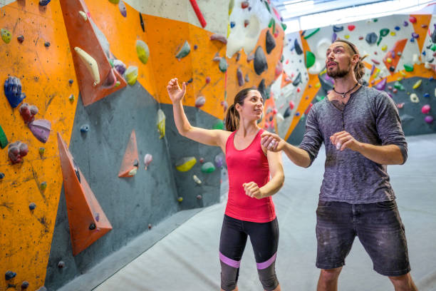 Young smiling brunette in sport suit looking at caucasian man with piercing during doing exercises in boulder centrum.