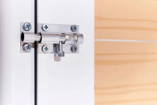 Aluminum manual latch bolt installed on a white lacquered aluminum carpentry door inside a home