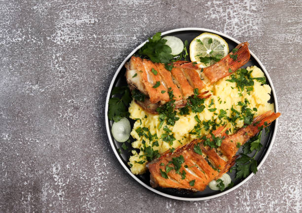 istock Fried fish and mashed potatoes with onions, lemon and parsley on a round plate on a dark background 1278250631