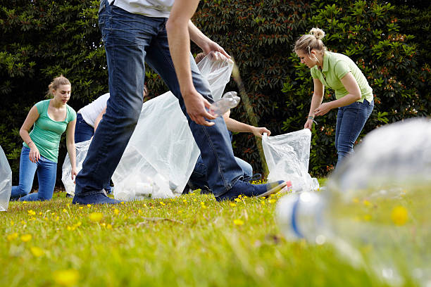 people cleaning up litter on grass - oppakken stockfoto's en -beelden