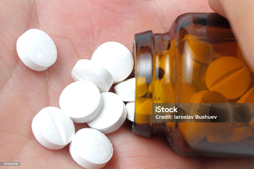 Pills poured into a palm from a bottle of dark glass, close-up. Aspirin Stock Photo