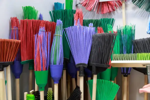 Sale of household goods, cleaning equipment for the house plastic broom brushes with a wooden handle different in the store on the showcase