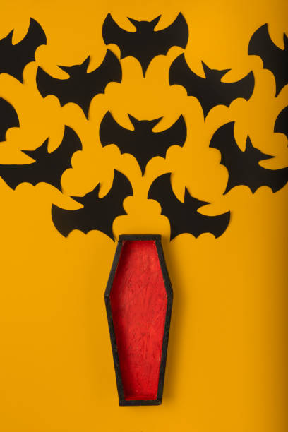 istock an open coffin with red padding from which black handmade paper bats fly out. halloween concept on yellow background 1278254142
