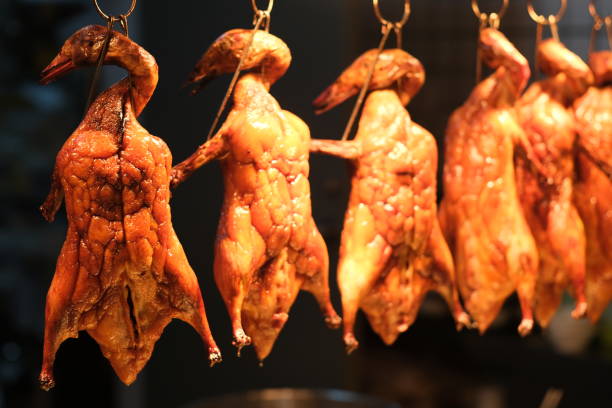 close up Cantonese cured duck hanging in a row. Dark background. Traditional Chinese food cantonese cuisine stock pictures, royalty-free photos & images