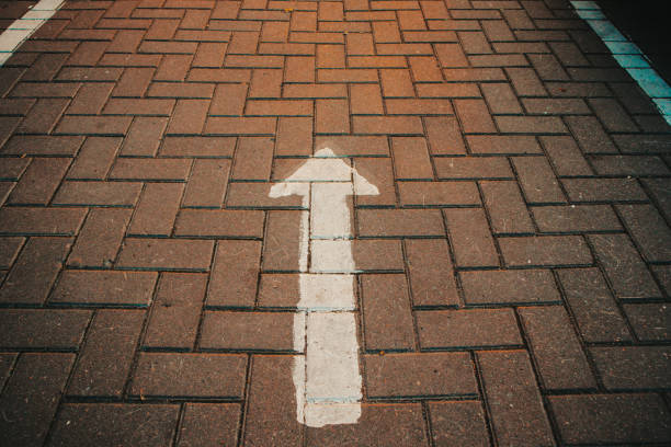 arrow on the asphalt footpath surface symbol concept direction escape