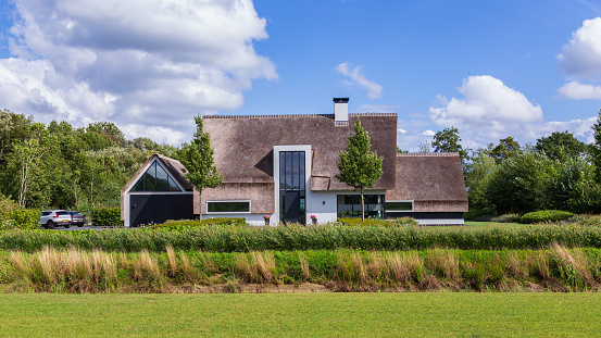 Barneveld, Netherlands- August 23, 2020: Newly build luxery white villa with thatched roof in Barneveld Holland