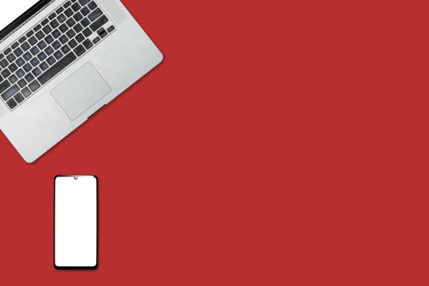 istock Open laptop with white smartphone. All with isolated screen on red background desk. 1278266103