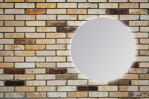 Round mirror near brick wall
