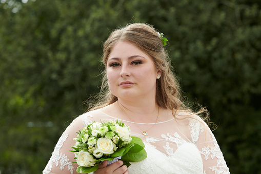 Real people wedding. Bride smiling into the camera. Outdoors shot in public park