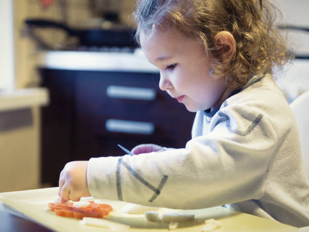 istock Two-year-old child cuts carrots and potatoes in kitchen 1278273065