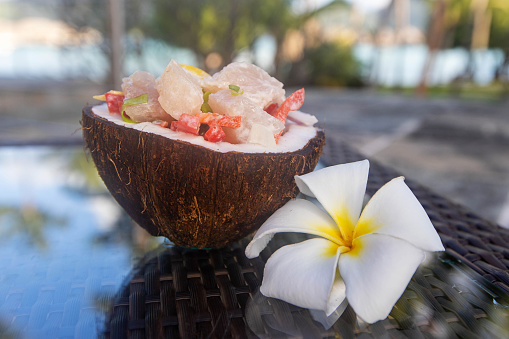 Un desayuno tropical de Poisson Cru servido en una cáscara de coco photo