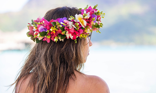 Pretty woman wears colorful flower crown while on tropical island vacation in Bora Bora, French Polynesia
