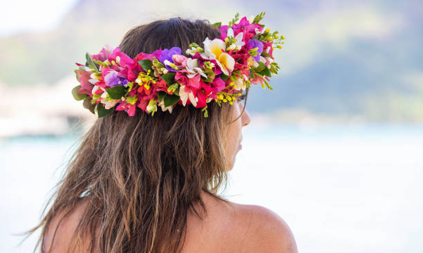 Beautiful woman wears a colorful floral crown on tropical island Bora Bora Pretty woman wears colorful flower crown while on tropical island vacation in Bora Bora, French Polynesia floral crown photos stock pictures, royalty-free photos & images