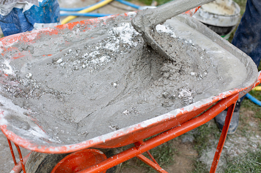 Wheelbarrow with sand, cement and lime-making mortar with hoe