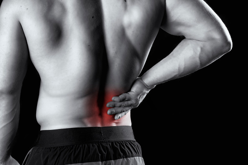 A man grasping his lower back shot in black and white with red added to signify the pain.