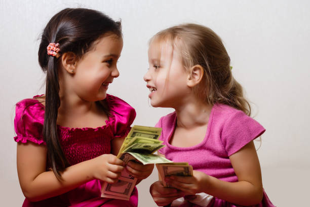 istock two little girls are playing with dollars on a white background 1278286777