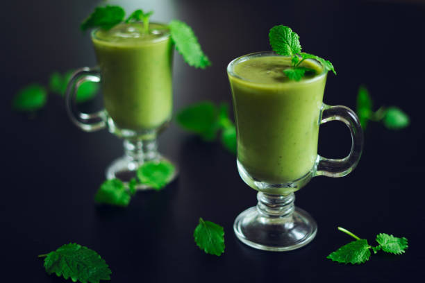 istock Fresh avocado smoothie poured into a glass with mint leaves on a black table. 1278287920