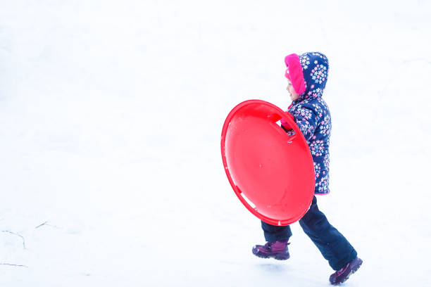 Cute litter girl sliding down on the snow mountain
