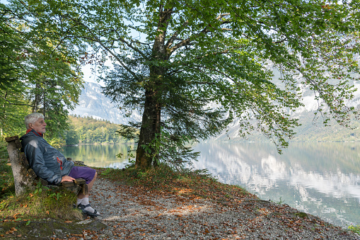 Senior men sitting on the bench on the lakeshore at the Lake Bohinj, Slovenia