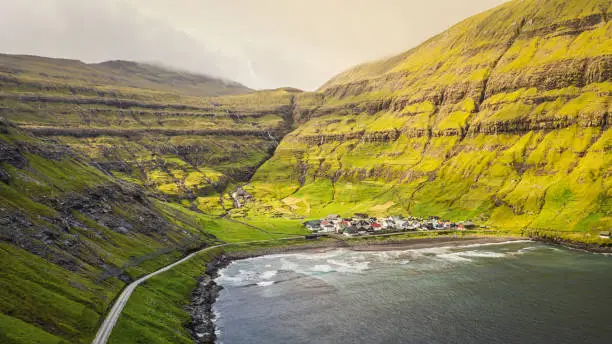 Panorama of Tjornuvik Fjord and Village, the northernmost village on Streymoy in the Sunda Municipality surrounded by tall and green mountain range in summer. Aerial Drone Point of View. Tjornuvik Town and Fjord, Sunda, Streymoy Island, Faroe Islands, Kingdom of Denmark, Nordic Countries, Europe