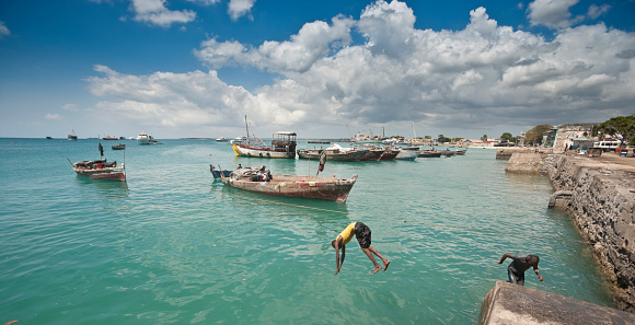 Stone Town, Zanzibar, Tanzania | October 21, 2007: Teenagers jumping in the turquoise sea at the harbour